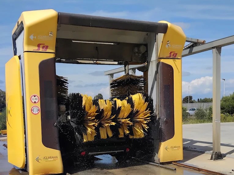 Portale Aquarama S9 con spazzole nere e gialle in rotazione su un veicolo tra schizzi d'acqua, cartello altezza 2,30