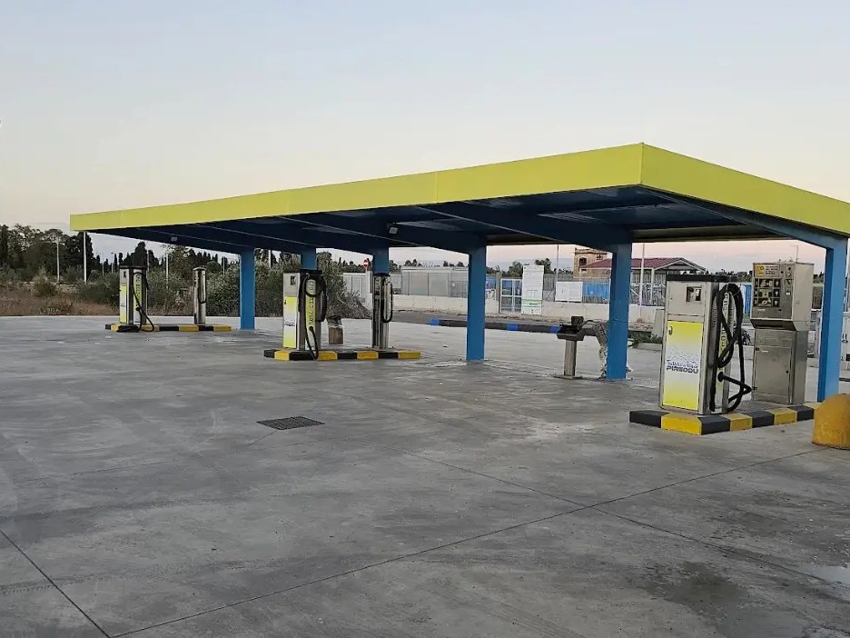 Pensilina gialla e blu della Bubble Car Wash Pireddu con colonnine self service su piazzale in cemento al tramonto