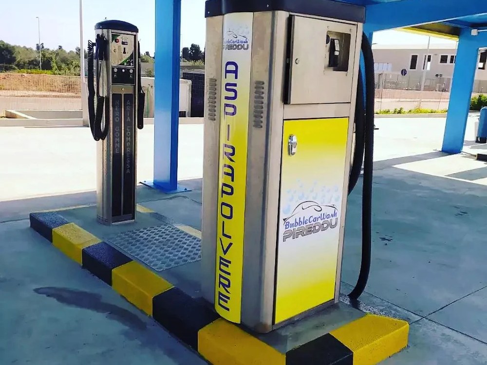 Colonnina Aspirapolvere in acciaio e giallo con logo Bubble Car Wash Pireddu accanto a erogatore gonfia gomme sotto pensilina blu
